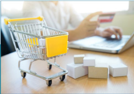 Shopping cart with boxed supplies beside a laptop